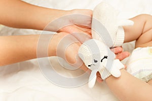 Hands of woman holds baby feet in the pair of knitted bootee