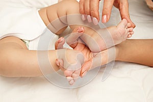 Hands of woman holds baby feet, blurred background
