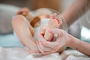hands woman holds baby feet soft focus background