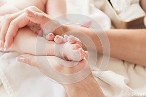 Hands of woman holds baby foot