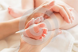 Hands of woman holds baby foot