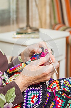 Hands of woman knitting a vintage wool quilt