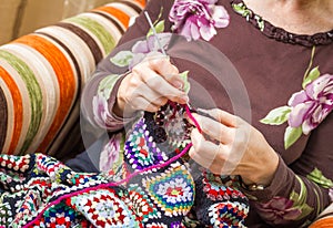 Hands of woman knitting a vintage wool quilt