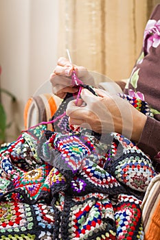 Hands of woman knitting a vintage wool quilt