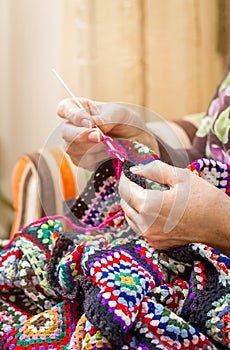 Hands of woman knitting a vintage wool quilt