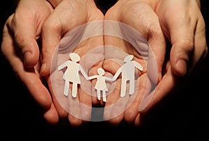 The hands of a woman and a man holding out a paper family, with the concept of conceiving a family.