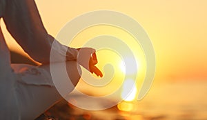 Hands of woman meditating in yoga pose at sunset on beach