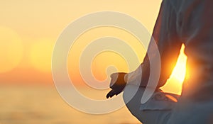 Hands of woman meditating in yoga pose at sunset on beach