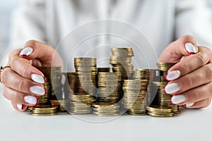 hands of a woman on a mirrored table with a roller coaster with coins hugging money.