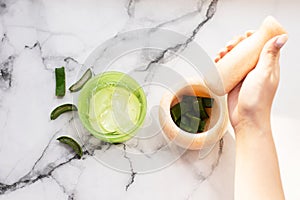 Hands of a woman mixing ingredients in mortar for natural aloe gel. sliced aloe leaf