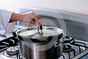 Hands of Woman opening a kitchen pot lid.