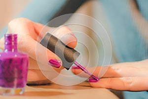 Hands of the woman painting nails bright varnish