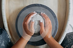 Hands of woman potter, ready to work with white clay at pottery wheel