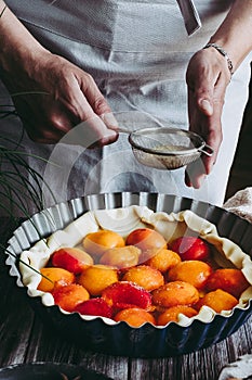 Hands of a woman preparing an apricot pie