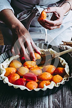 Hands of a woman preparing an apricot pie