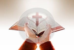 Hands of Woman Raise up a Bible for Praying with Blurred Shape o