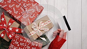 Hands of woman in red sweater holding credit card and gift box on white background close-up,top view,flat lay,copy space.Christmas