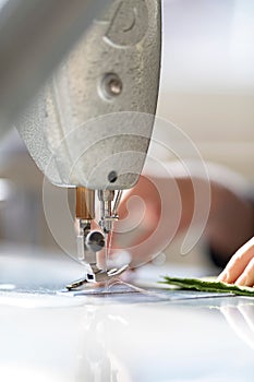 Hands of woman sewing cloth on machinery