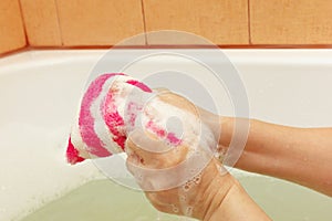 Hands of woman soaping striped sponge with soap