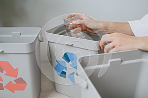 Hands of a woman sorting garbage beween small recycle bins at home photo