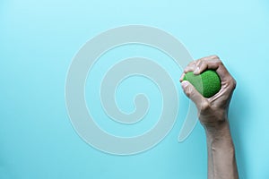 Hands of a woman squeezing a stress ball on green background