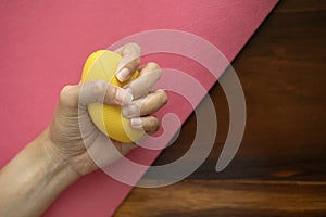 Hands of a woman squeezing a stress ball on the yoga mat