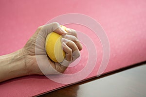 Hands of a woman squeezing a stress ball on the yoga mat in the exercise class for healthy
