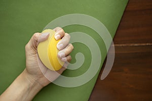 Hands of a woman squeezing a stress ball on the yoga mat, work out concpet