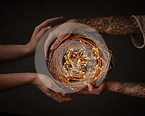 The hands of a woman with a tattoo and the men`s hands hold a festive wreath with fringes around the black background