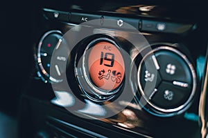 Hands of woman turning car air conditioning system. Button on dashboard to cold air in new car - orange panel. Photo of climate