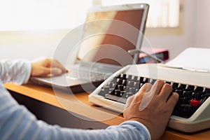 Hands of woman typing both typewriter and laptop on working desk in office