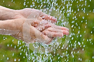 Hands of woman under summer rain