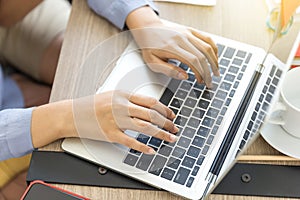 The hands of a woman are using a laptop computer to working at home.