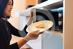 Hands woman using microwave oven with bread in home kitchen