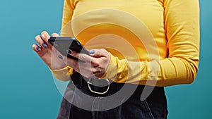 Hands of woman using mobile phone on blue background. Technology, social network, internet concept.