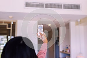 Hands woman using a remote control to activating air conditioning to 25 degree celsius,Concept save energy and save world