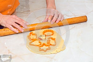 Hands of a woman using a rolling pin and preparing biscuits from dough