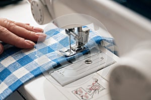 Hands of a woman using a sewing machine