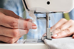 Hands of a woman using a sewing machine