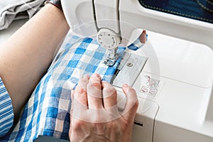 Hands of a woman using a sewing machine