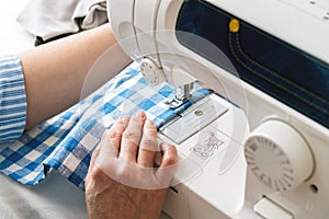 Hands of a woman using a sewing machine in tailor shop