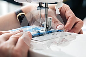 Hands of a woman using a sewing machine in tailor shop