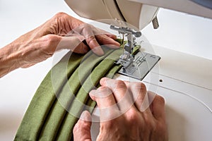 Hands of a woman using a sewing machine to sew homemade cloth face masks