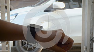 Hands of woman using smart watch to open and close lock and unlock the door of car metaphor remote security application concept