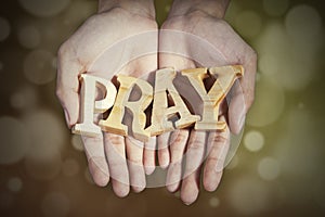 Hands with a word of pray in bokeh background