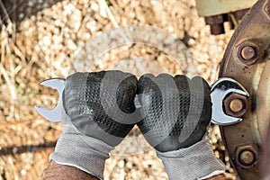 Hands with Work Gloves Holding a Wrench and Tighten very Rusty Bolts