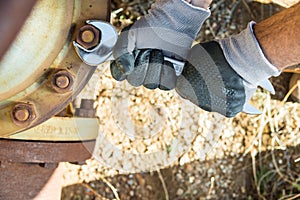 Hands with Work Gloves Holding a Wrench and Tighten very Rusty Bolts