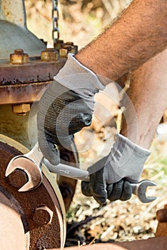 Hands with Work Gloves Holding a Wrench and Tighten very Rusty Bolts