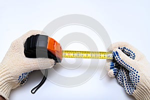 Hands of a worker, builder in protective gloves halding a ruler, using tape measure against white background