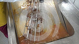 Hands of worker cleans fat on the industrial grill.